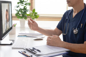 オンライン診療のメリットや注意点を正しく理解し、適切な受診方法を決定するために、モニター越しに医師による専門的な診察や相談を受けている様子の写真